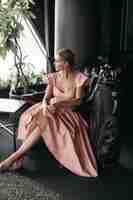 Foto grátis foto de uma encantadora senhora caucasiana sentada na poltrona de couro preto e posa para a câmera