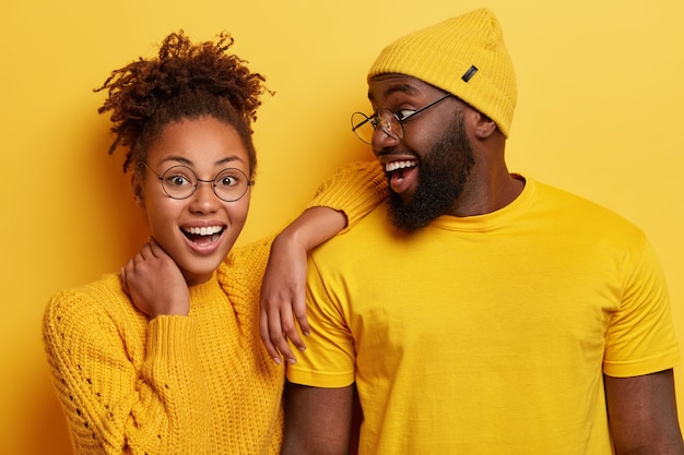 Foto de uma garota afro feliz se apoiando no ombro do namorado, sentindo-se feliz, ficando perto, expressando emoções positivas