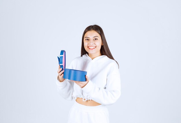 Foto de uma jovem modelo segurando uma caixa de presente em forma de coração.