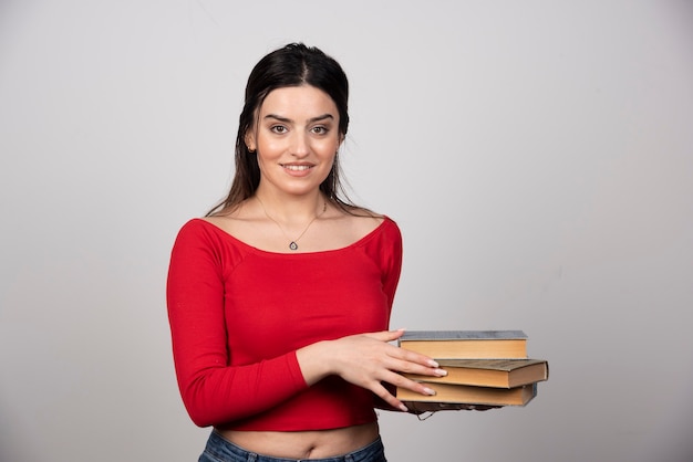 Foto de uma linda mulher segurando uma pilha de livros.