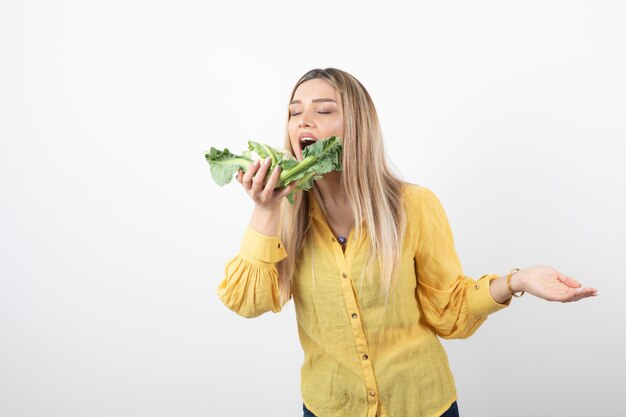 Foto de uma modelo de mulher bonita bonita em pé e tentando comer couve-flor.