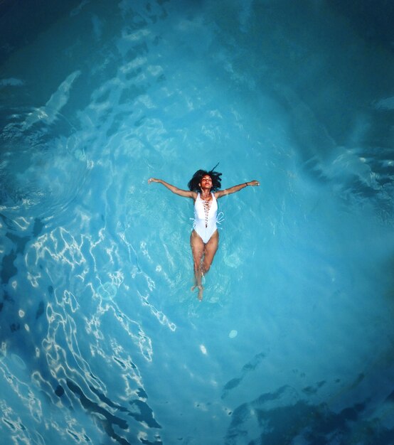 Foto de uma mulher africana em Monokini branco nadando no corpo de água