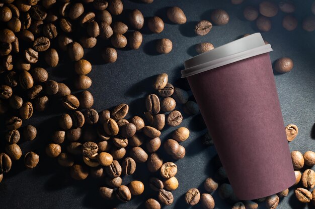 Foto de uma xícara de café de papel com uma mistura de grãos arábica e robusta ao fundo.