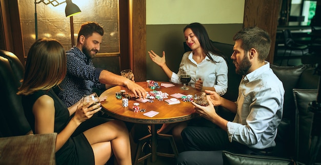 Foto de vista lateral de amigos masculinos e femininos, sentado à mesa de madeira.