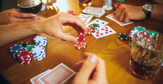 Foto de vista lateral de amigos masculinos e femininos, sentado à mesa de madeira.