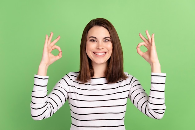 Foto do bom humor da moça bonita mostra anúncios de símbolo de ok dedos isolados sobre fundo de cor verde. Foto Premium