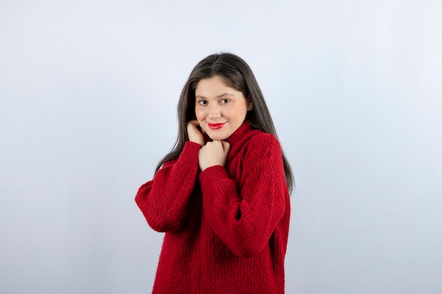 Foto do retrato de uma jovem modelo com um suéter vermelho quente em pé e posando