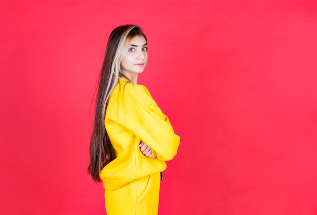 Foto do retrato de uma modelo de garota séria em pé e posando com os braços cruzados