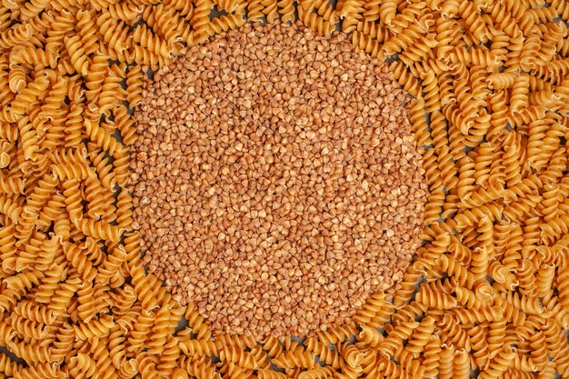 Foto em alta resolução de trigo sarraceno no meio de massas italianas cruas alinhadas em círculo com vista aérea