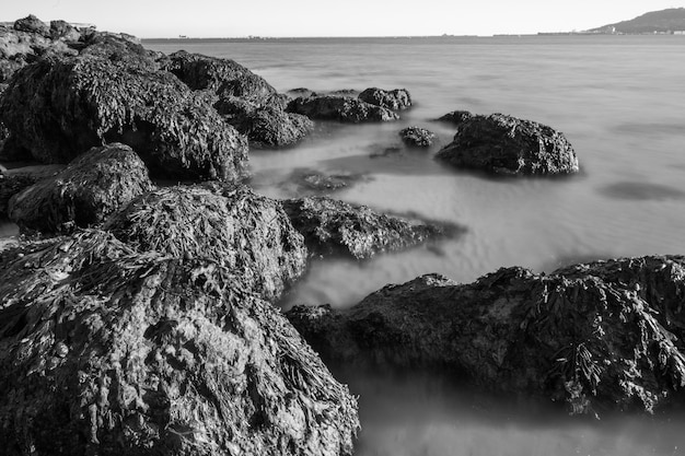 Foto em preto e branco das rochas e do mar muito borrado da praia Sandsfoot em Dorset, Reino Unido