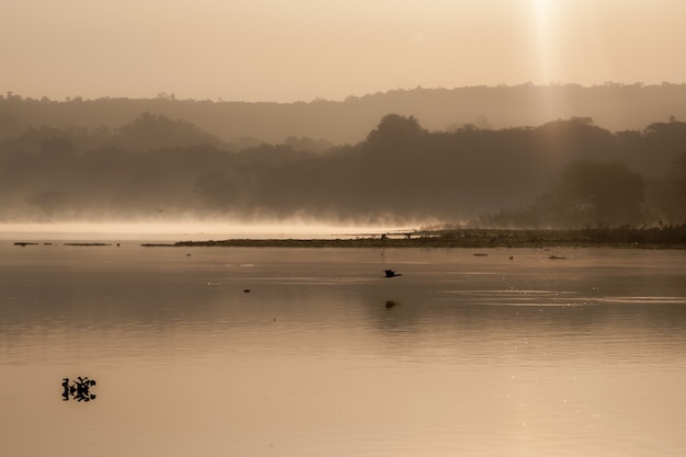 Foto em sépia da água do lago cercada por árvores e montanhas