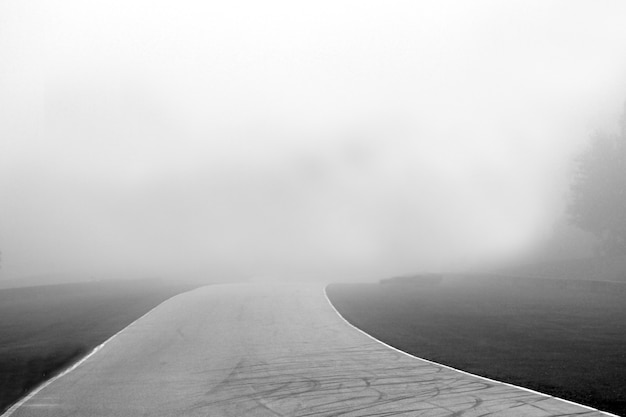 Foto em tons de cinza de um caminho com fundo nebuloso