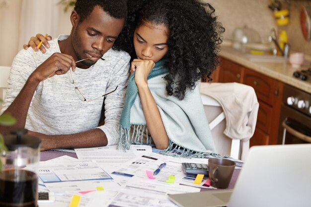 Foto espontânea interna de um homem e uma mulher africanos calculando despesas juntos