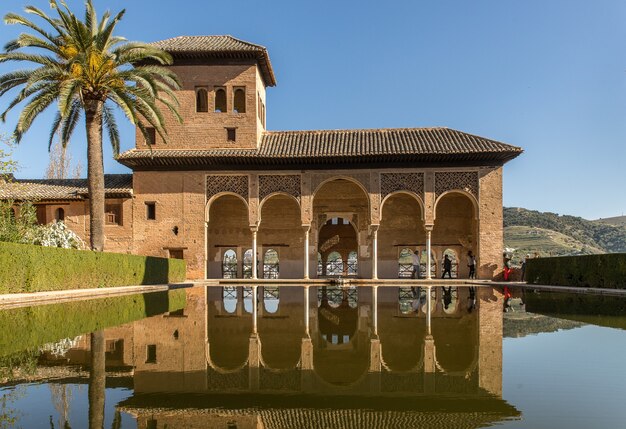 Foto grande angular de um prédio em frente à água e ao lado da árvore na Espanha