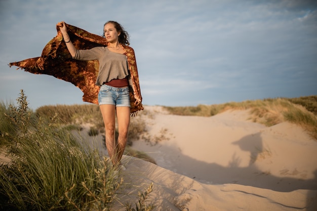 Foto grande angular de uma mulher caminhando na areia durante o dia