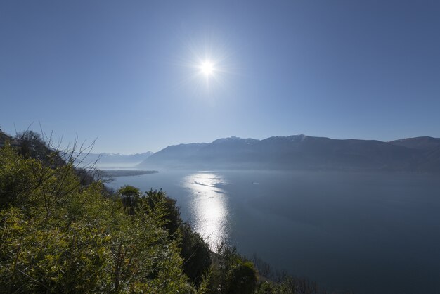 Foto grande angular do sol brilhando sobre a água e as montanhas