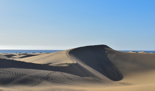 Foto hipnotizante de dunas de areia contra um céu azul em Gran Canaria, Espanha