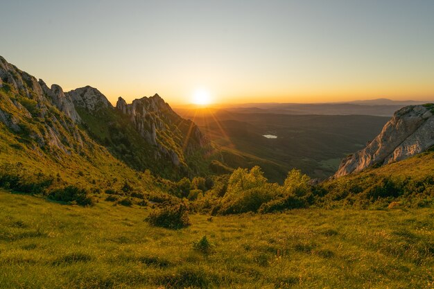 Foto hipnotizante de uma colina rochosa verde durante a bela hora do pôr do sol