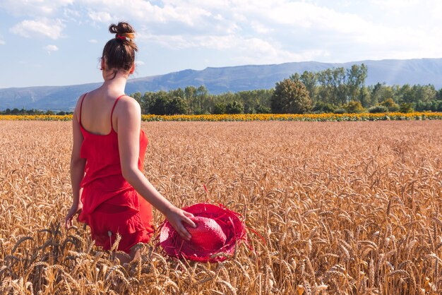 Foto hipnotizante de uma mulher atraente em um vestido vermelho em um campo de trigo
