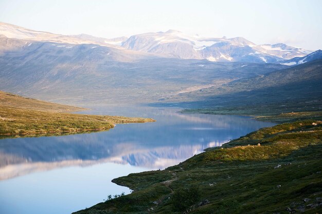 Foto horizontal da bela vista do lago calmo, terreno verde e montanhas