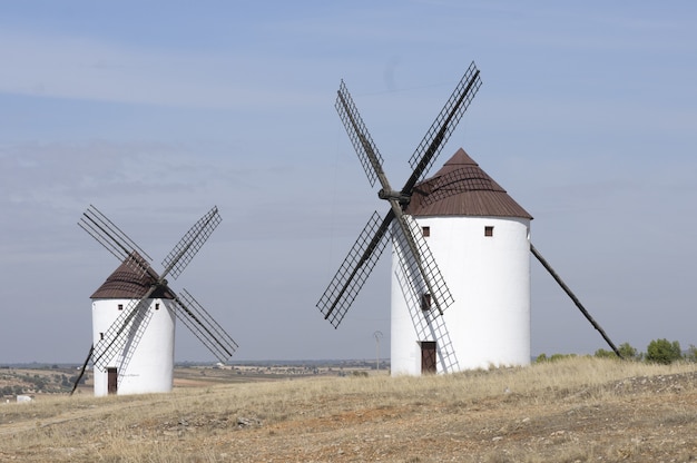 Foto horizontal de dois moinhos brancos em um campo vazio em Belmonte, Espanha