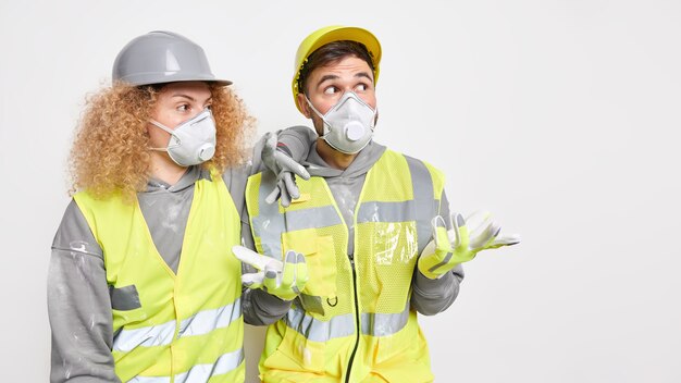 Foto grátis foto horizontal de dois trabalhadores da construção civil usando máscaras protetoras de capacete e uniforme