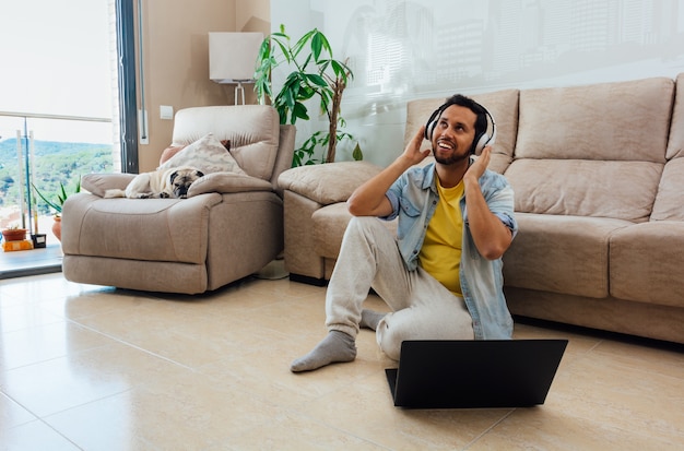 Foto grátis foto horizontal de um homem sentado no chão em frente a um laptop ouvindo música