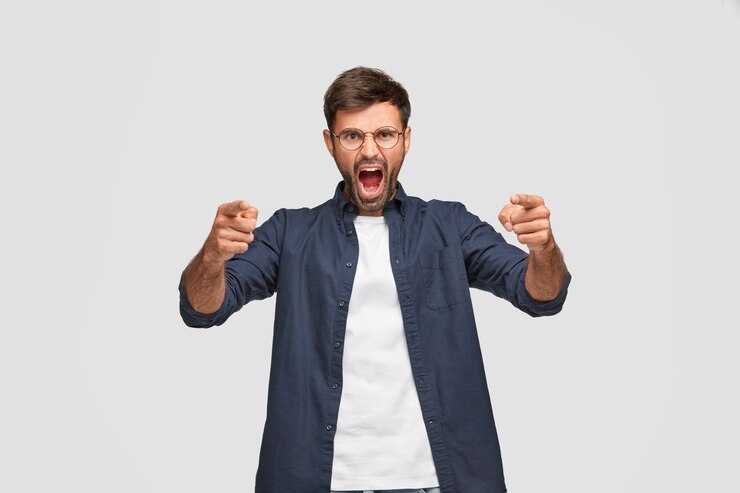 Foto grátis foto horizontal de um homem zangado e furioso com uma expressão irritada, gritando com alguém, apontando com os dois dedos indicadores para a câmera