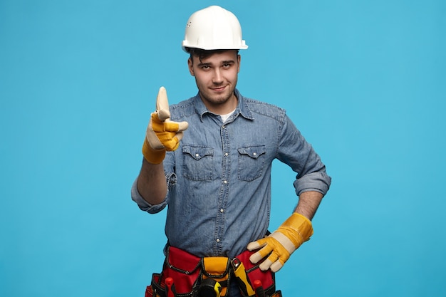 Foto horizontal de um jovem e bonito trabalhador de serviço de manutenção usando capacete branco