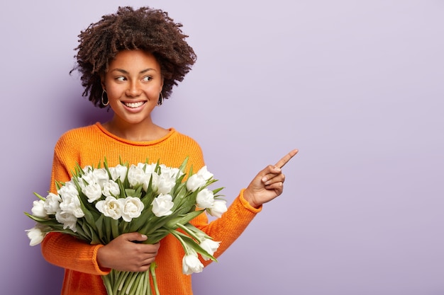 Foto horizontal de uma mulher encantada de pele escura com cabelo afro