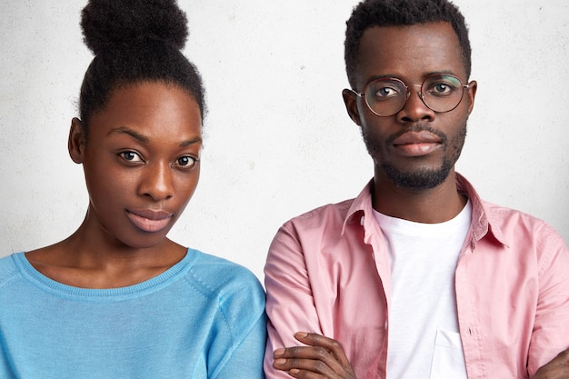 Foto grátis foto horizontal interna de looks masculinos e femininos afro-americanos atrativos e confiantes com expressão séria para a câmera. reúna-se para discutir planos futuros