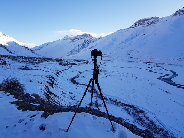 Foto incrível de uma cordilheira coberta de neve no primeiro plano de um suporte para câmera