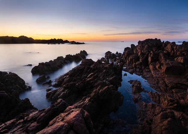 Foto incrível de uma praia rochosa ao pôr do sol