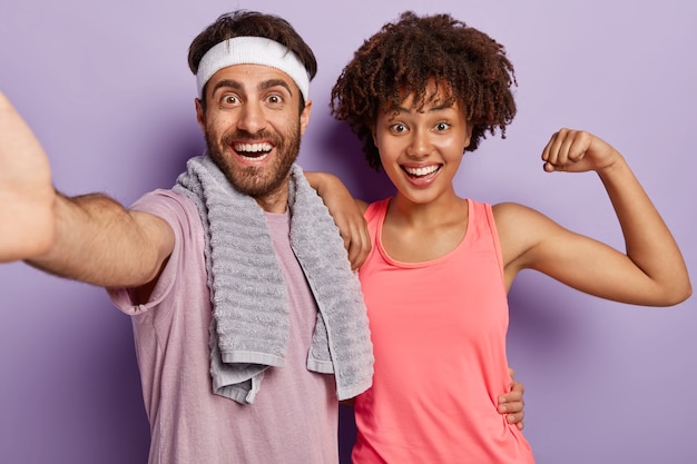 Foto grátis foto interna de um casal alegre e diverso para manter os músculos flexíveis, fazer exercícios diários, usar roupas esportivas e olhar de perto para a câmera com uma expressão feliz