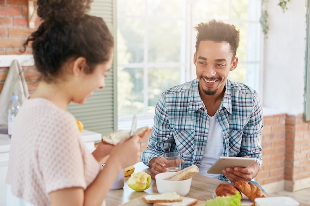 Foto interna de um homem barbudo feliz com aparência específica, usa um computador tablet