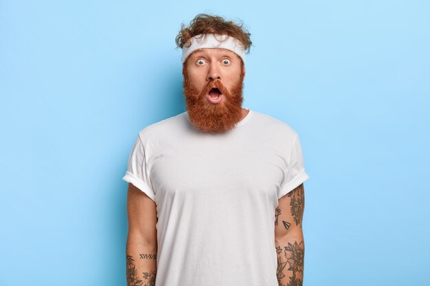 Foto interna de um homem barbudo surpreso com cabelo ruivo que olha com espanto e faz ginástica todos os dias