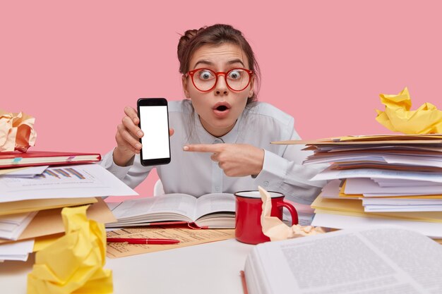 Foto interna de uma mulher bonita surpresa com pontos de expressão facial de medo na tela em branco do telefone inteligente