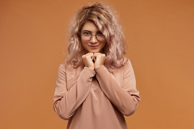 Foto isolada de linda jovem encantadora com cabelo rosado e sorriso fofo, sentindo-se tímida