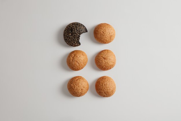 Foto isolada de um escuro feito de tinta de choco e outros pães de hambúrguer branco, espumante com sementes de gergelim, isolado. Preparando lanche de fast food. Dois pãezinhos redondos de sanduíche. Receita de padaria. Conceito de comida