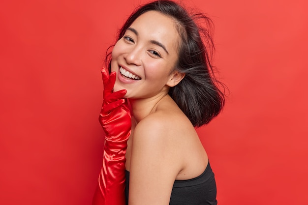 Foto lateral de uma mulher asiática feliz com cabelos escuros flutuando no ar e sorrisos usando roupas elegantes, tem uma beleza natural, feliz por passar o tempo livre na festa