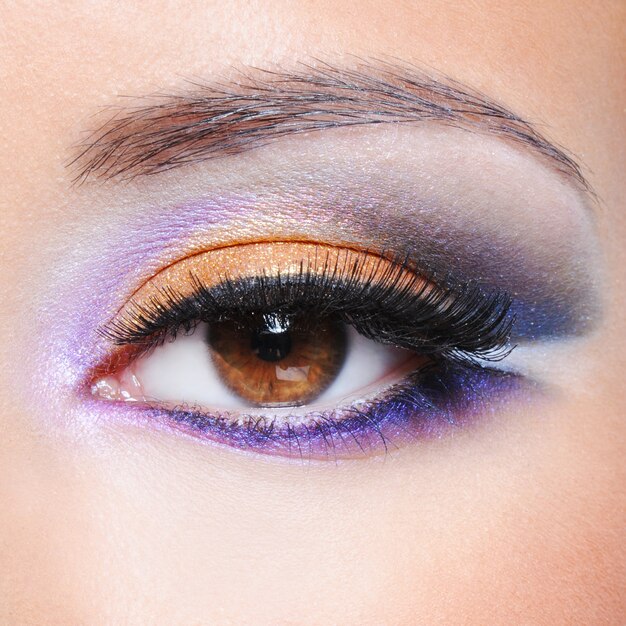 Foto macro de um olho feminino com maquiagem saturada de moda