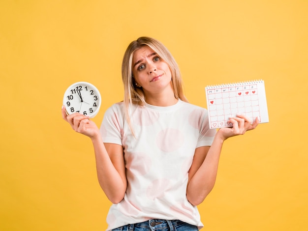 Foto média da mulher segurando o relógio e calendário do período