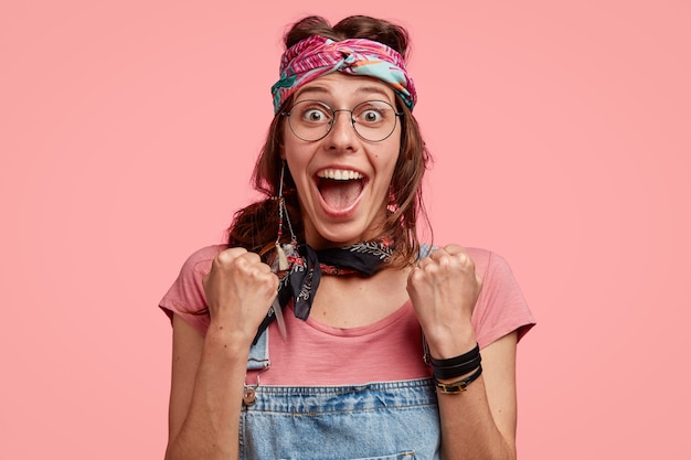 Foto grátis foto na cabeça de uma hippie maravilhada usando roupas elegantes e fechando os punhos de felicidade