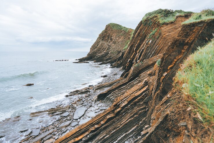 Foto grátis foto panorâmica de penhascos cheios de grama verde ao lado do mar azul durante o dia