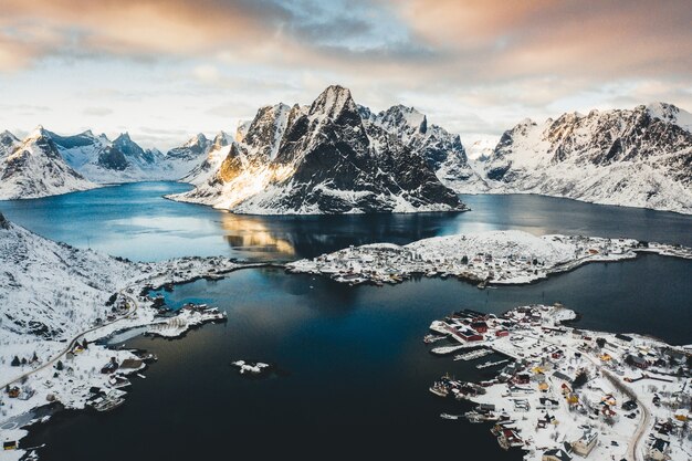 Foto panorâmica de uma cidade costeira perto de um corpo de água com montanhas nevadas