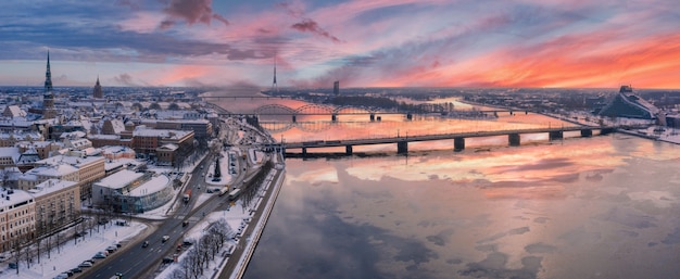 Foto panorâmica do belo pôr do sol sobre a cidade coberta de neve de Riga com o rio Daugava e o centro da cidade