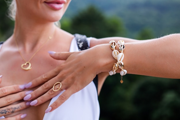 Foto próxima das mãos da mulher com um anel e uma pulseira com joias