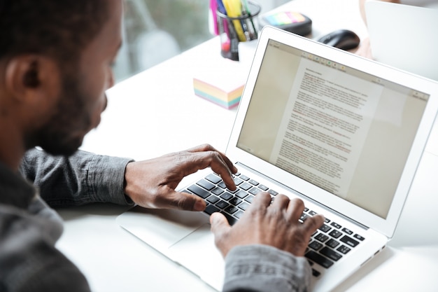 Foto recortada de homem jovem sério, sentado no escritório coworking