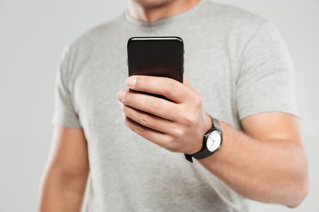 Foto recortada de jovem usando telefone celular conversando.