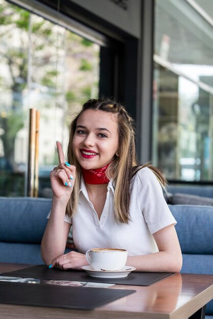 Foto vertical da bela senhora sentada no restaurante e sorrindo para a câmera